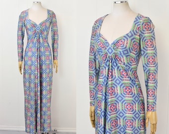 Könnte beinhalten: Ein langärmliges Maxikleid mit einem geometrischen Muster in Blautönen, Grün, Rosa und Weiß. Das Kleid hat einen V-Ausschnitt und eine geraffte Taille.