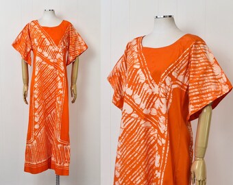 May include: A long orange dress with a white tie-dye pattern. The dress has a scoop neck and short sleeves.