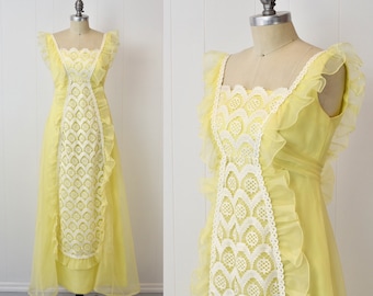 May include: A yellow maxi dress with white lace detailing and ruffled trim. The dress has a square neckline and sleeveless design.