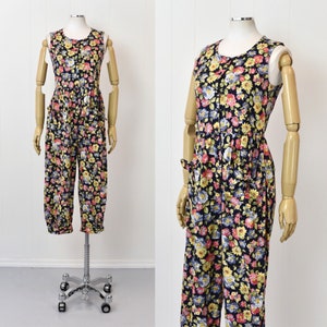 May include: A sleeveless floral jumpsuit with a button-up front and two pockets. The jumpsuit is made of a lightweight fabric and has a relaxed fit.