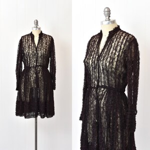 May include: A black lace dress with long sleeves and a ruffled hem. The dress has a fitted bodice and a flowing skirt.