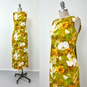 May include: A vintage maxi dress with a green background and a large floral print in white and yellow. The dress has a sleeveless design and a simple, straight silhouette.