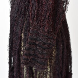 May include: Close-up of a black and burgundy lace fabric with a ruffled texture.