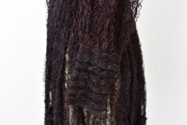 May include: Close-up of a black and burgundy lace fabric with a ruffled texture.