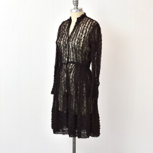 May include: A black lace dress with a ruffled design, displayed on a mannequin.