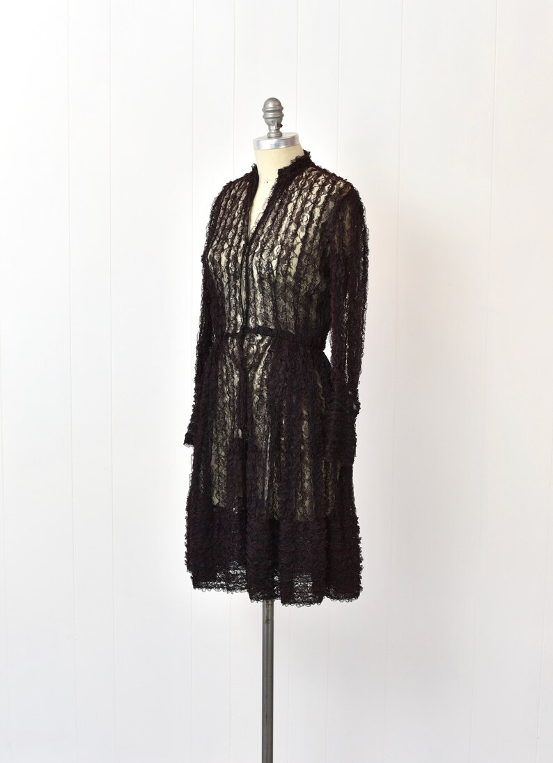 May include: A black lace dress with a ruffled design, displayed on a mannequin.