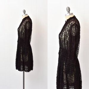 May include: A black lace dress with a high neck and long sleeves. The dress is fitted through the bodice and has a flared skirt.