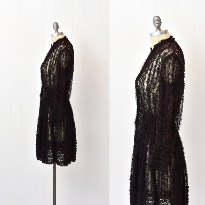 May include: A black lace dress with a high neck and long sleeves. The dress is fitted through the bodice and has a flared skirt.