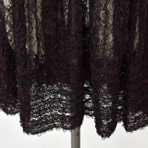 May include: Black lace fabric with a ruffled edge. The lace is delicate and has a vintage feel.