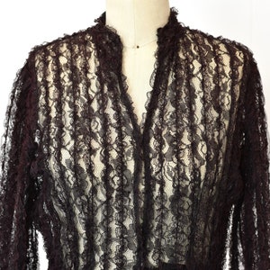 May include: A black lace top with a ruffled collar and long sleeves.