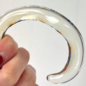 May include: A clear glass bangle with a brown and blue swirl design.