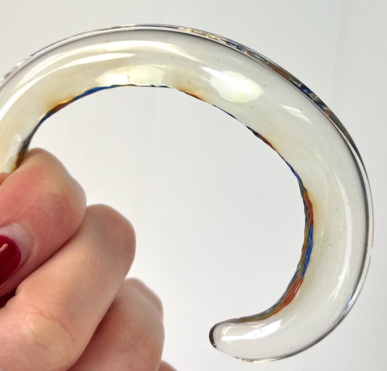 May include: A clear glass bangle with a brown and blue swirl design.
