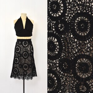 May include: A black crochet skirt with a circle pattern. The skirt is knee-length and has a flared silhouette.