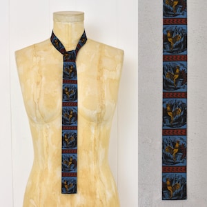 May include: A vintage necktie featuring a repeating pattern of a rooster in a landscape scene. The tie has a blue background with red and black accents. The tie is displayed on a mannequin.