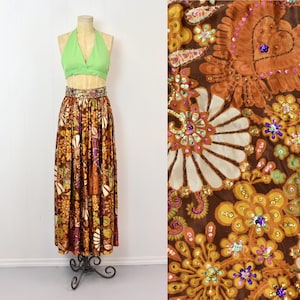 May include: A long brown maxi skirt with a floral print and gold sequins. The skirt has a high waist and a flowing silhouette.
