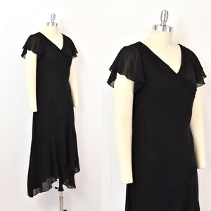 May include: A black dress with a V-neck and flutter sleeves. The dress has a beaded trim on the neckline and a diagonal beaded detail on the skirt. The skirt has an asymmetrical hemline, creating a layered effect.
