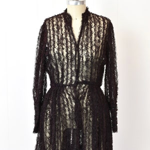 May include: A black lace dress with long sleeves and a ruffled hem. The dress is sheer and has a fitted bodice.