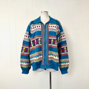 May include: A teal blue jacket with a colorful geometric pattern. The jacket has a zipper closure and long sleeves.