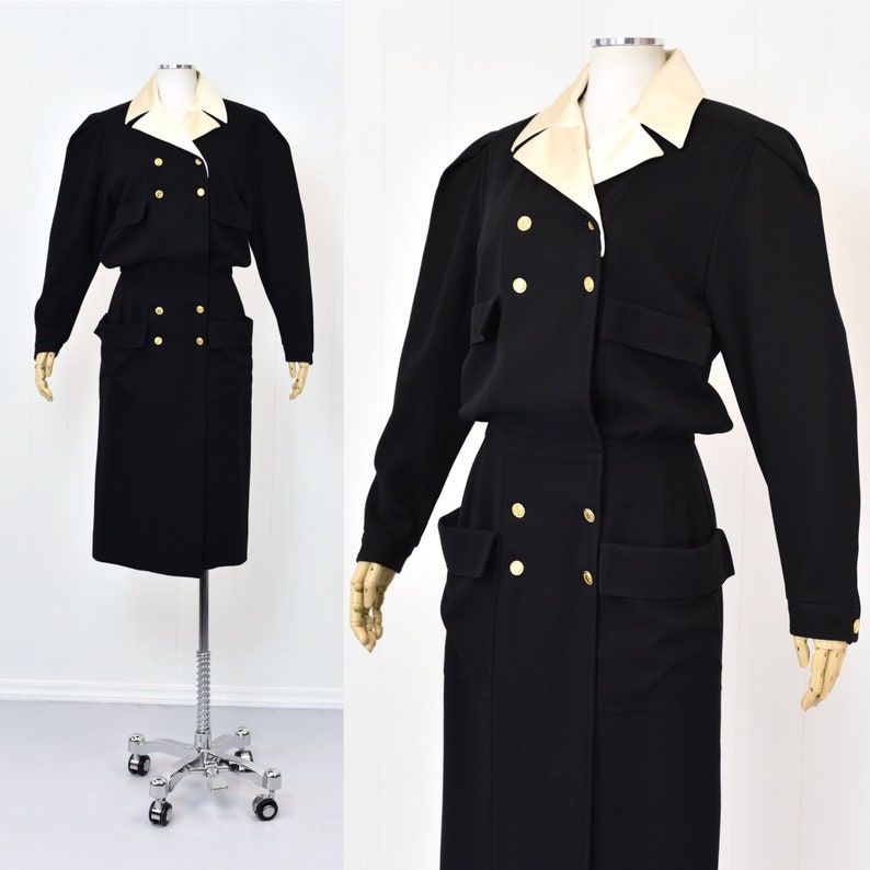 May include: A black double-breasted dress with a white collar and gold buttons. The dress has two large pockets on the front and a skirt that falls to the knees.