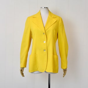 May include: A bright yellow blazer with a classic design, featuring a notched collar, three button closure, and two front pockets.