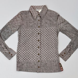 May include: A long-sleeved button-down shirt with a brown and white geometric pattern. The shirt has a collar and a button-up front.