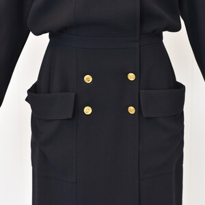 May include: A black long-sleeved dress with a double-breasted button closure and two large pockets on the front.