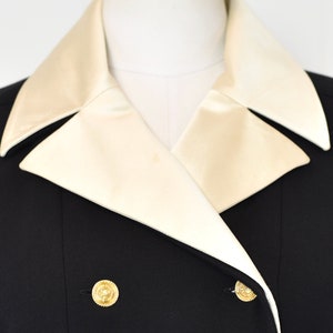 May include: A black double-breasted blazer with a white satin collar. The blazer has gold buttons.