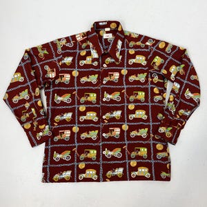 May include: A maroon button-down shirt with a repeating pattern of vintage cars, gold coins, and blue chain links. The long-sleeved shirt has a classic collar and buttoned cuffs. The cars are in various colors, including green, yellow, and white.