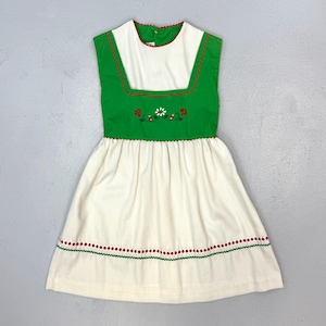 May include: A sleeveless dress with a white skirt and a green bodice. The bodice has a white square neckline and is decorated with embroidered flowers and ladybugs. Red and green trim accents the dress.