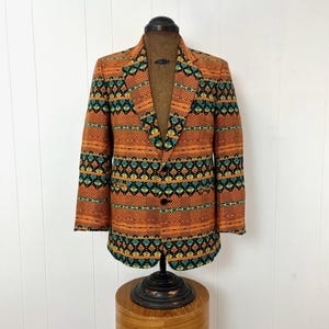 May include: A vintage blazer with a geometric pattern in shades of orange, green, black, and yellow. The blazer has a single button closure and two pockets.