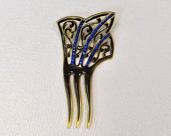May include: A gold hair comb with a decorative design featuring blue rhinestones. The comb has four tines.