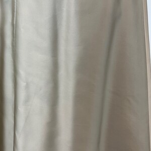 Op de afbeelding: Een close-up van een lichtbeige rok met een rits. De rok is gemaakt van een gladde, zijdeachtige stof.