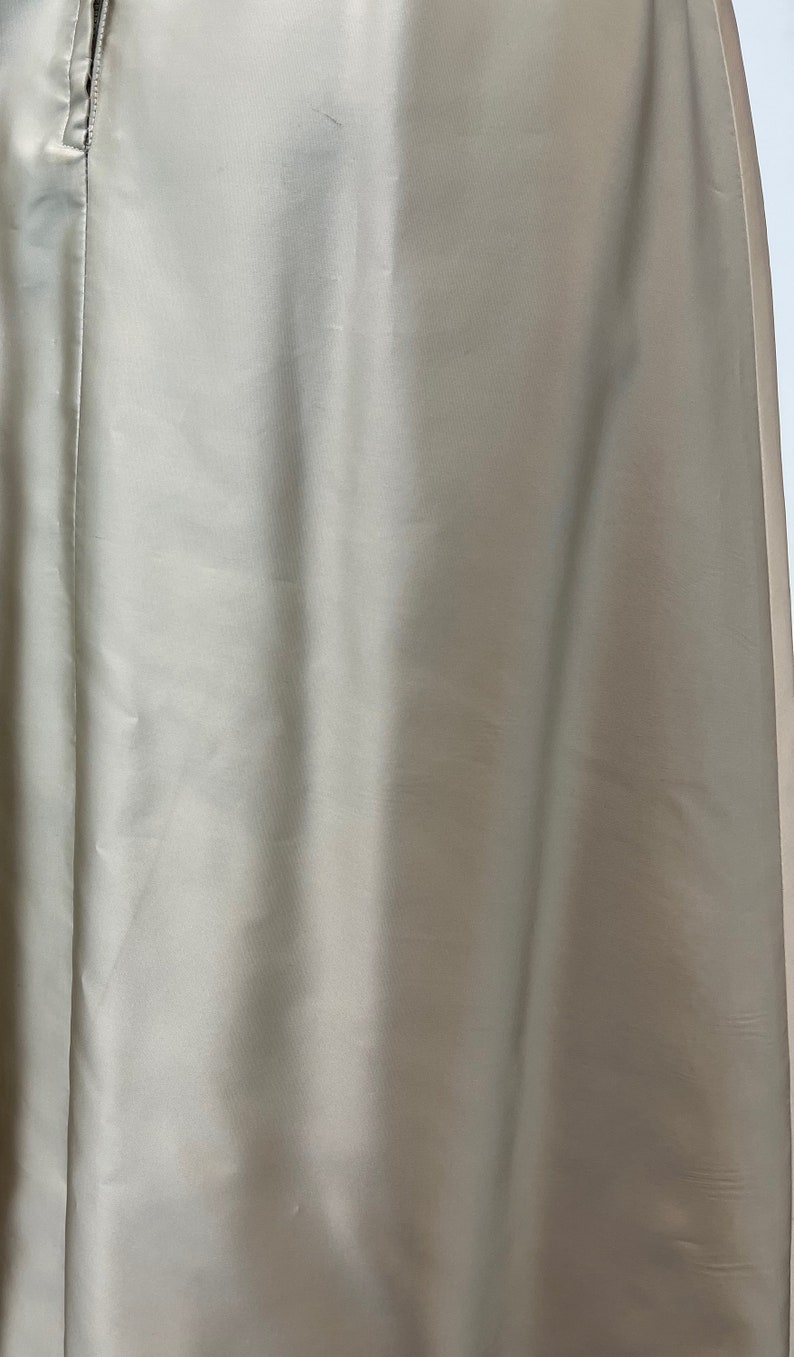 Op de afbeelding: Een close-up van een lichtbeige rok met een rits. De rok is gemaakt van een gladde, zijdeachtige stof.