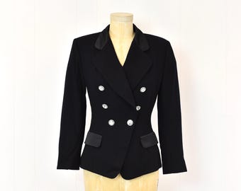 May include: Black double-breasted blazer with satin lapels and pocket trim. The jacket features six decorative silver buttons and is displayed on a mannequin. The blazer is a classic style, suitable for formal or business attire.