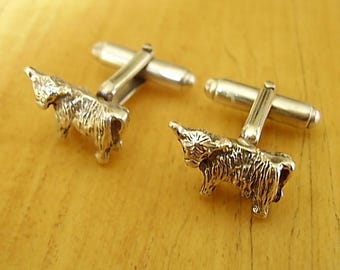 May include: A pair of silver cufflinks featuring a detailed, three-dimensional design of a Highland cow.