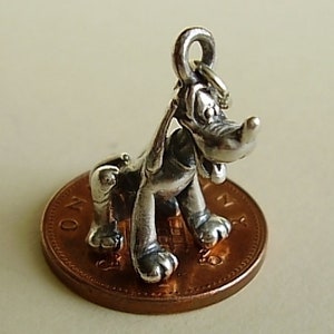 Könnte beinhalten: Silberner Anhänger von Pluto, dem Hund aus Disney, der auf einem Penny steht.