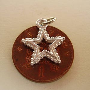 Puede incluir: Encanto de plata en forma de estrella con un borde de cuentas. El encanto est&aacute; sentado en una moneda de color cobre.
