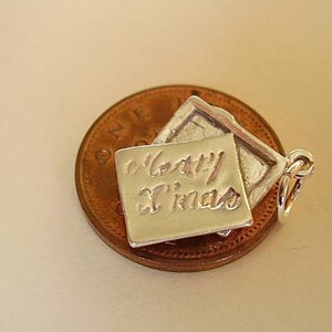 May include: Silver charm in the shape of a folded card with the inscription "Happy Xmas".