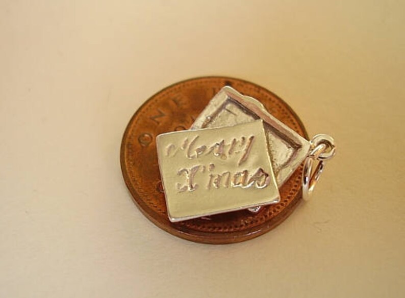 May include: Silver charm in the shape of a folded card with the inscription "Happy Xmas".