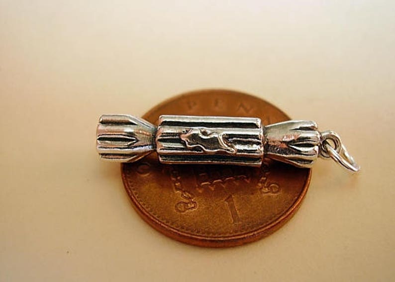 Puede incluir: Encanto de plata en forma de cracker de Navidad. El encanto est&aacute; detallado con una superficie texturizada y un peque&ntilde;o dise&ntilde;o en el lateral.