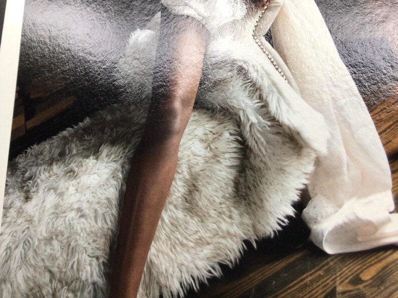 May include: A plush, off-white faux fur throw blanket with a thick, shaggy texture. The blanket features a soft, dense pile and a light cream colour throughout, providing a voluminous and cosy appearance with its long, synthetic fibres.