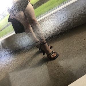 May include: A pair of black strappy high-heeled sandals with a square toe design and thin ankle straps. The footwear features a minimalist construction with slender straps crossing over the top of the foot and a slim heel for elevation.