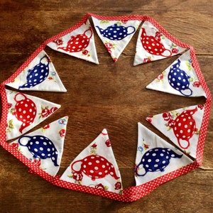 May include: A white and red bunting with a red and white polka dot trim. Each flag features a white teapot with blue polka dots and red flowers.