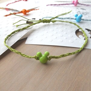 May include: A green string bracelet with a green Mickey Mouse charm.