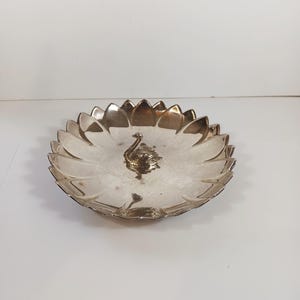 May include: Silver-toned decorative dish with a lotus flower design. The dish features a detailed swan figurine in the center. The edges of the dish are shaped like petals, creating a unique and elegant look.
