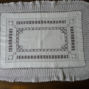 Puede incluir: Mantel de encaje blanco tejido a crochet con un delicado patrón floral. El mantel tiene un borde festoneado y es perfecto para una cena formal.