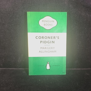 May include: A vintage Penguin Books paperback titled Coroner's Pidgin by Margery Allingham. The cover features a green and white horizontal tri-band design with the Penguin logo, the text Complete Unabridged, and the price 2/6 at the bottom.