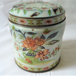 Peut inclure: Une boîte vintage en étain bleu et blanc avec un motif floral. La boîte est ronde et a un couvercle avec une bordure dorée.