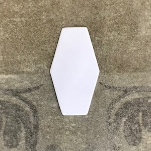 May include: White ceramic hexagon-shaped plate with rounded edges.