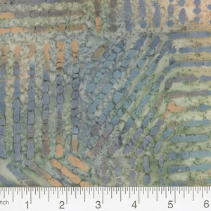 May include: Close-up of fabric with a repeating pattern of blue, orange, and gray shapes on a mottled green and white background. The design includes vertical and diagonal lines of oblong shapes, creating a textured appearance. A ruler is at the bottom.